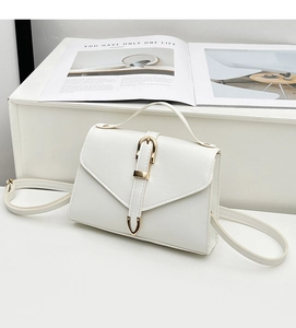 Detailed side view of white faux leather crossbody bag with polished gold U-shaped buckle