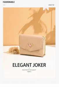 Close-up of trifold beige wallet with heart emblem and decorative plush ball charm