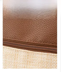 Detail of woven straw and brown leather bag showing durable double-stitched zipper seams