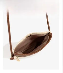 Detail view of woven straw bag interior with brown leather trim and golden magnetic clasp