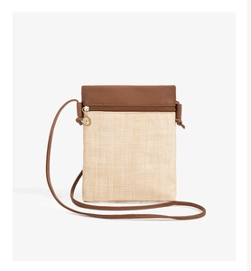 Detail of straw crossbody bag featuring brown leather trim and golden metal ring zipper