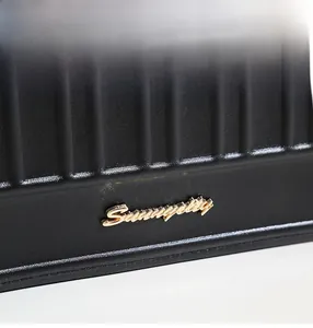 Détail du cuir noir gaufré avec logo Summerty en métal doré sur le sac à main