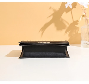 Vue détaillée du fond en accordéon d'un sac en cuir noir avec un logo en métal doré
