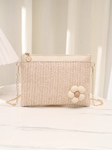 Détail d'un sac bandoulière tissé beige orné d'une fleur en tissu et chaîne dorée