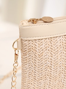 Détail du tissage en paille beige avec fermeture éclair dorée et bandoulière chaîne