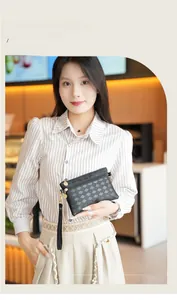 Detail of black checkered woven clutch featuring a gold zipper and detachable wrist strap