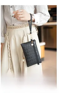 Close-up of black woven leather mini bag with golden zipper and logo charm detail