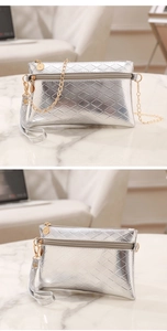 Close-up of silver diamond quilted handbag featuring gold zipper and metal chain strap
