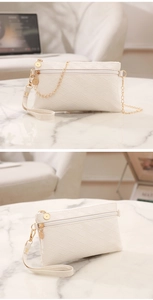 Detail of white quilted handbag with golden chain strap and double zipper compartments