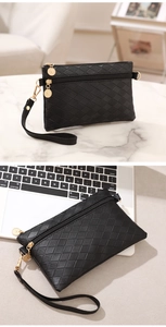 Detail of black quilted double zipper clutch with wristlet and gold hardware details
