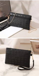 Detailed view of black quilted mini bag with gold chain and wrist strap on marble surface