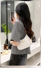 Mirror selfie showing the white quilted shoulder bag with gold metal logo detail