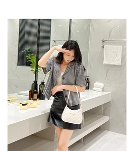 Close-up of white quilted baguette bag paired with a chic houndstooth blazer outfit