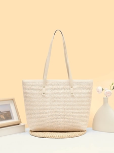 Detailed view of woven straw tote bag texture with reinforced synthetic leather straps