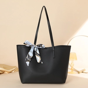 Nahaufnahme einer schwarzen Totebag mit Litschi-Prägung und dekorativem gepunktetem Seidenschal