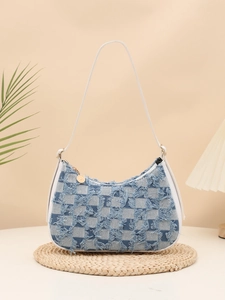 Detail of blue checkerboard denim shoulder bag with fringe edges and gold pendant