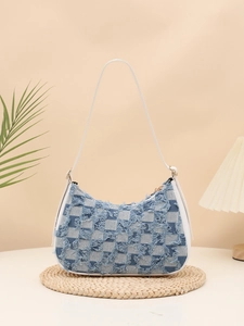 Close-up of blue and white checkered denim underarm bag with frayed tassel edge details