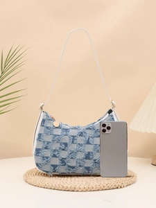 Detail of blue checkerboard denim shoulder bag with fringe texture and white strap