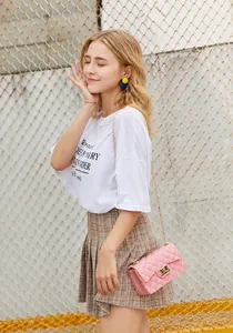Outdoor shot of a pink quilted jelly bag with gold chain strap and metal lock detail