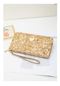 Détail de pochette longue à paillettes dorées avec ornement papillon blanc et dragonne