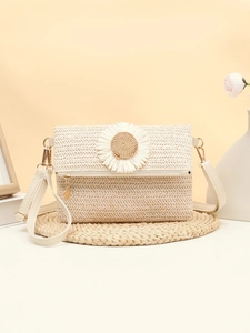 Detailed texture of straw crossbody bag featuring large daisy floral applique and leather strap