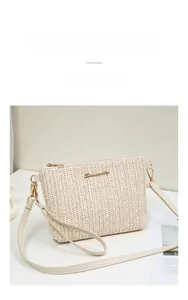Detail of woven straw bag with golden logo plaque and detachable cream shoulder strap