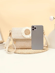 Detailed view of beige straw bag featuring a white daisy flower and white leather strap