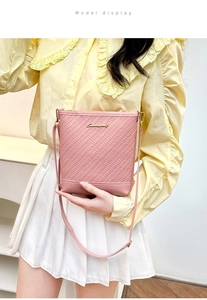 Detailed view of pink bucket bag with woven leather texture and gold logo logo