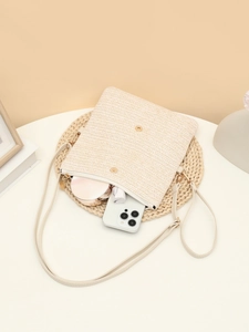 Detail of straw crossbody bag interior capacity with phone and cosmetics layout