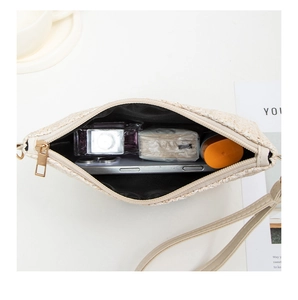 Detail showing the inner storage of a beige woven clutch with essentials and zipper
