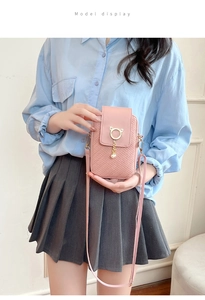 Close-up of pink textured crossbody phone bag with gold cat-ear ring and pearl charm