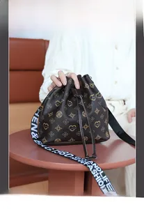 Detail of drawstring bucket bag featuring retro monogram pattern and wide letter strap