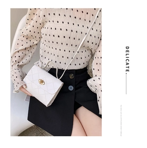 Model wearing a white quilted small crossbody bag with a golden turn-lock closure