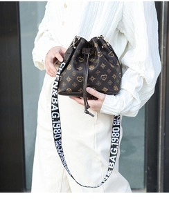 Detail of drawstring bucket bag with monogram print and wide lettered shoulder strap