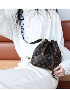 Detail of vintage drawstring bucket bag with monogram pattern and jacquard shoulder strap