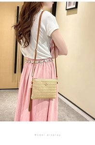 Modèle portant un sac bandoulière en paille avec logo fleur dorée et sangle en cuir