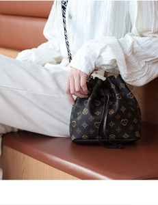 Detail of drawstring bucket bag with monogram pattern and lettered wide strap