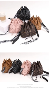 Detail of drawstring bucket bags in multiple colors featuring lettered wide straps