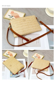 Gros plan sur le sac enveloppe en paille avec logo floral doré et bandoulière en cuir