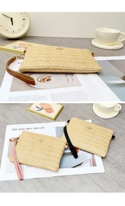 Détail du tissage en paille en V et de la boucle trèfle dorée sur la pochette