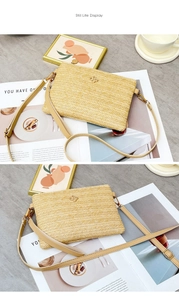 Détail du sac bandoulière en paille tissée avec logo floral doré et bandoulière en cuir
