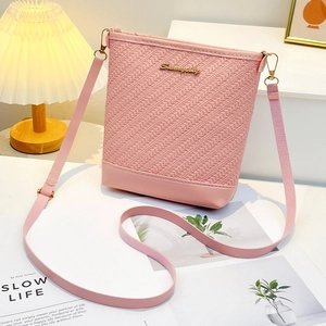 Pink embossed bucket bag with woven texture and gold logo in a stylish setting