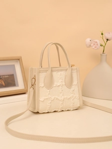 Detail of beige tote bag with pleated grid texture, metal hooks and leather handle