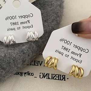 Vista macro dettagliata di orecchini a tripla spirale in rame con finitura opaca oro e argento
