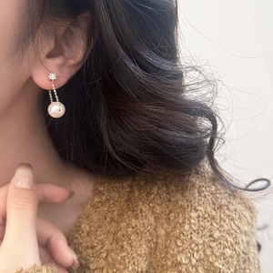 Detail of elegant long tassel earrings with high-luster pearls on a model ear