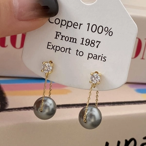 Close-up of long tassel earrings with 100% copper gold chains and grey pearls