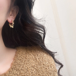 Primo piano di orecchini a cerchio dorati con ciondoli a cuore indossati da una modella