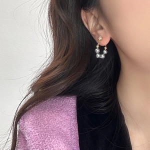 Elegant gold pearl earrings with five grey pearls and zircon on a model's ear