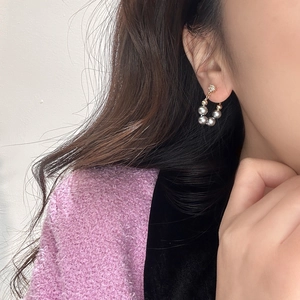 Macro detail of elegant hoop earrings with grey pearls and sparkling zircon on model