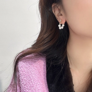 Detailed close-up of a pearl hoop earring with gold accents on a person's ear